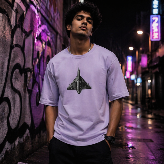 Person wearing a light purple t-shirt with a fighter jet graphic in an urban setting at night.